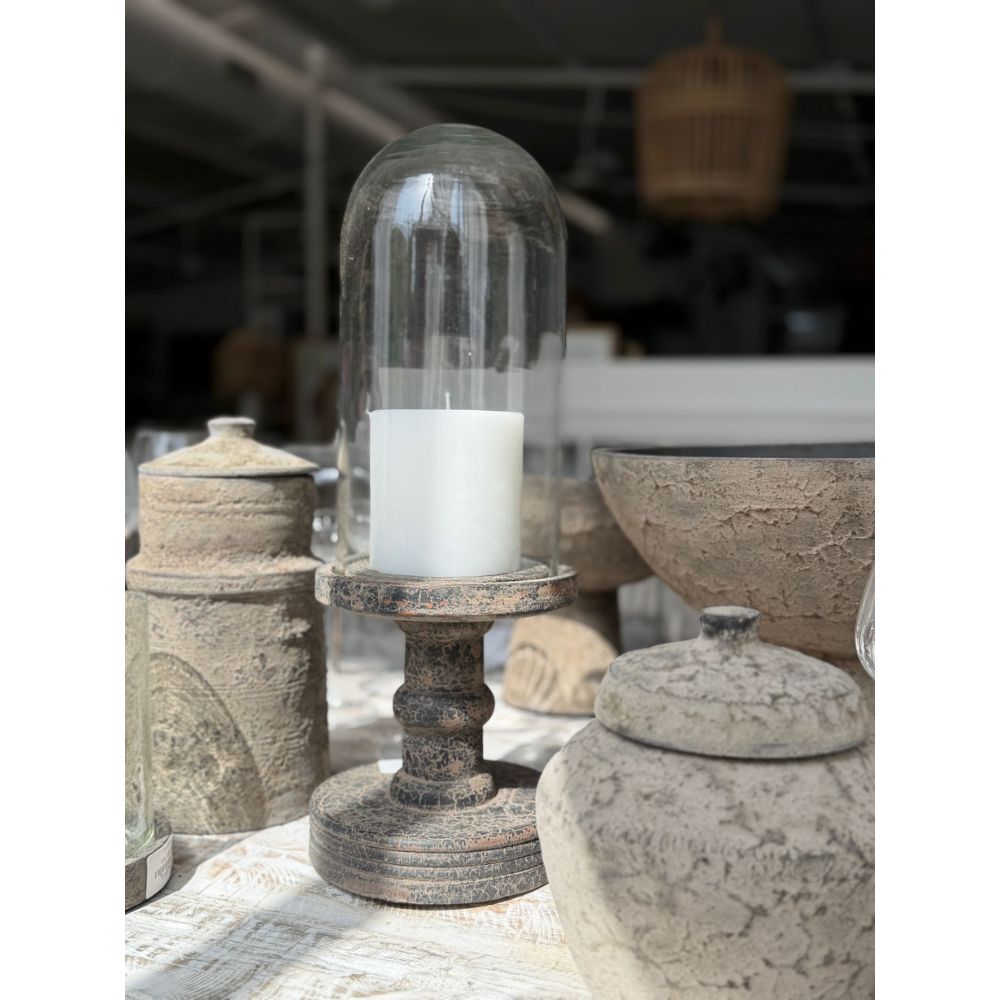 נרות עמוד לבנים מתחת ל"פעמון זכוכית צר על רגל מעץ" מבית Fine Lab Home מונחים בין צנצנות וקערות קרמיקה מחוספסות בחדר מואר באור השמש — פריט דקורטיבי מקסים לכל חלל.