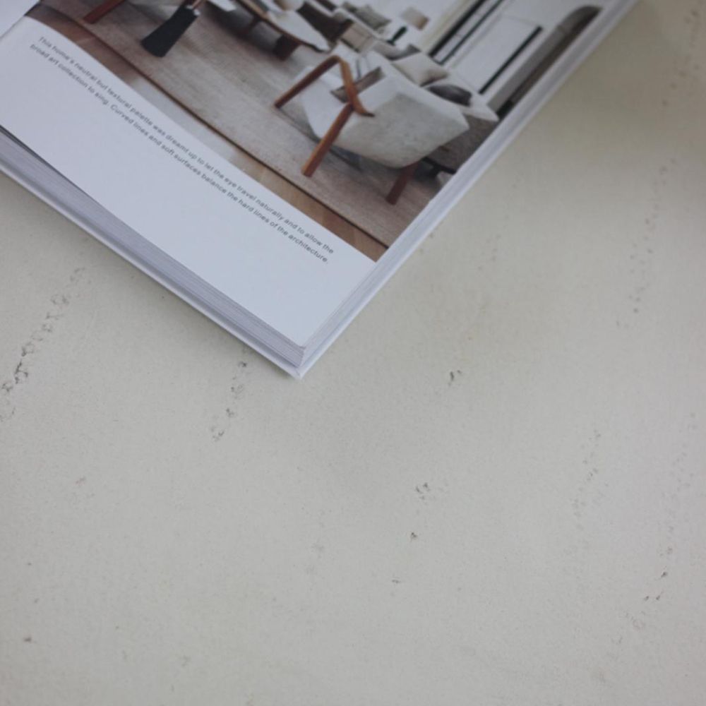 מגזין פתוח מציג סלון מודרני עם שולחן סלון עגול דמוי אבן מסוגנן מבית Fine Lab Home, המונח על משטח בהיר ומרקם.