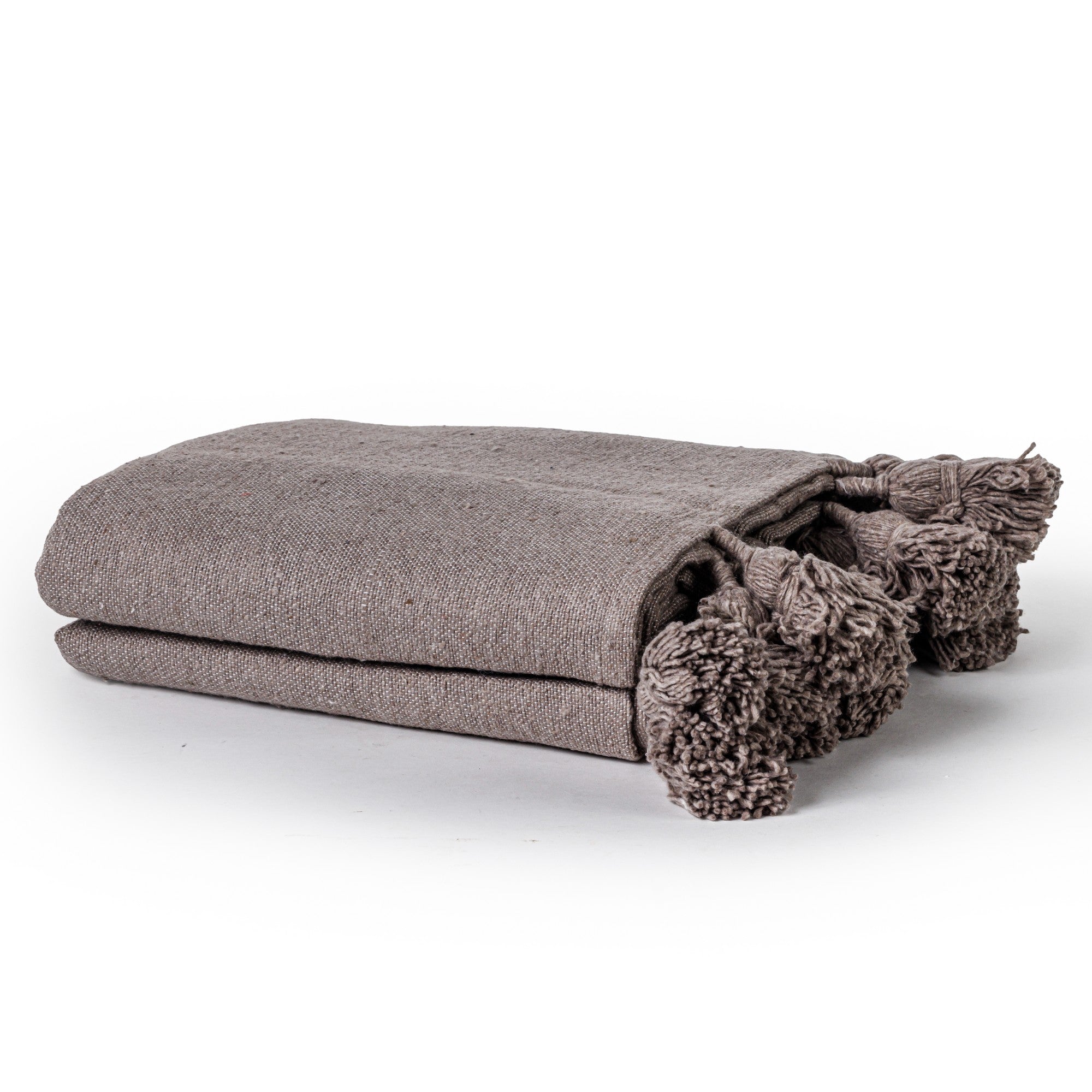 שמיכת מרקש עם פונפונים מבית Fine Lab Home, בגוון אפור עם מרקם ופרטי פונפונים בפינות, מונחת על רקע לבן – מושלמת ככיסוי מיטה דקורטיבי או כשמיכה בסגנון מרוקאי.