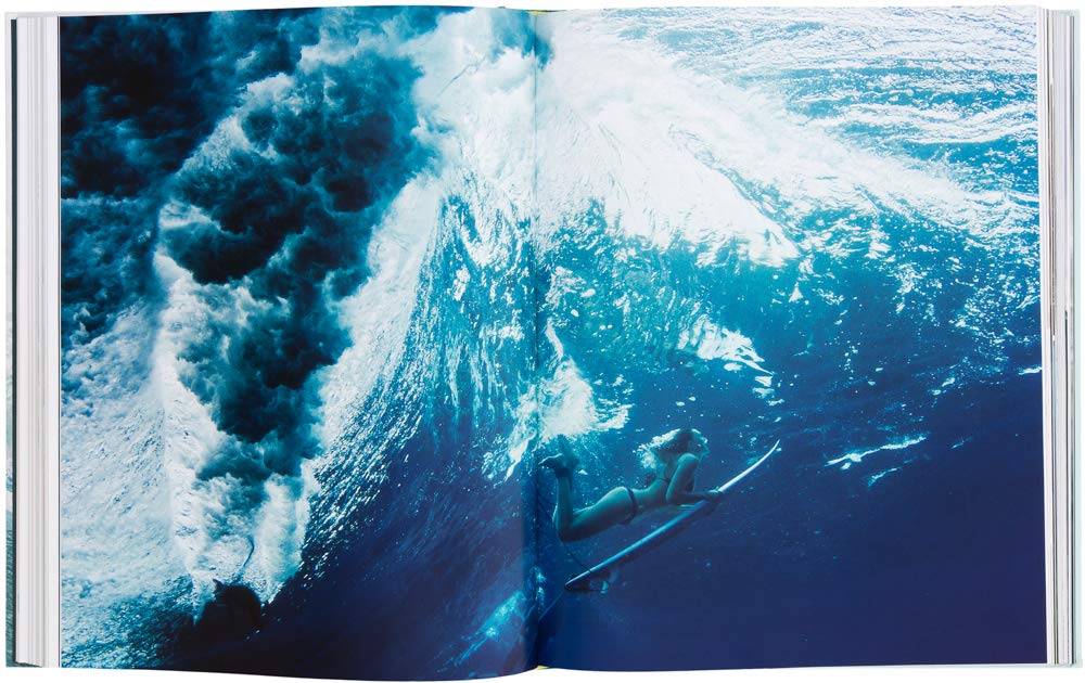 ספר פתוח על תמונה תת-מימית של גולש מתחת לגל נשבר — אידיאלי לחובבי תרבות הגלישה ולאוהבי יצירות איקוניות כמו ספר העיצוב surf odyssey של Fine Lab Home.