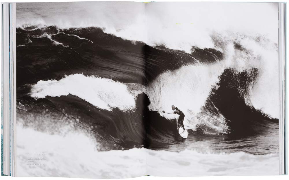 גולש רוכב על גל ענק בתמונה בשחור-לבן המשתרעת על פני שני עמודים בספר העיצוב Surf Odyssey של Fine Lab Home, המוקדש לתרבות הגלישה.