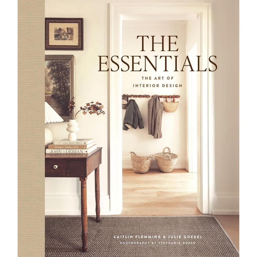 ספר העיצוב "The Essentials" של Fine Lab Home מציג במסעפתו מסדרון מעוצב עם שולחן עץ, מנורה, ספרים וכניסה עם סלים ומעילים.