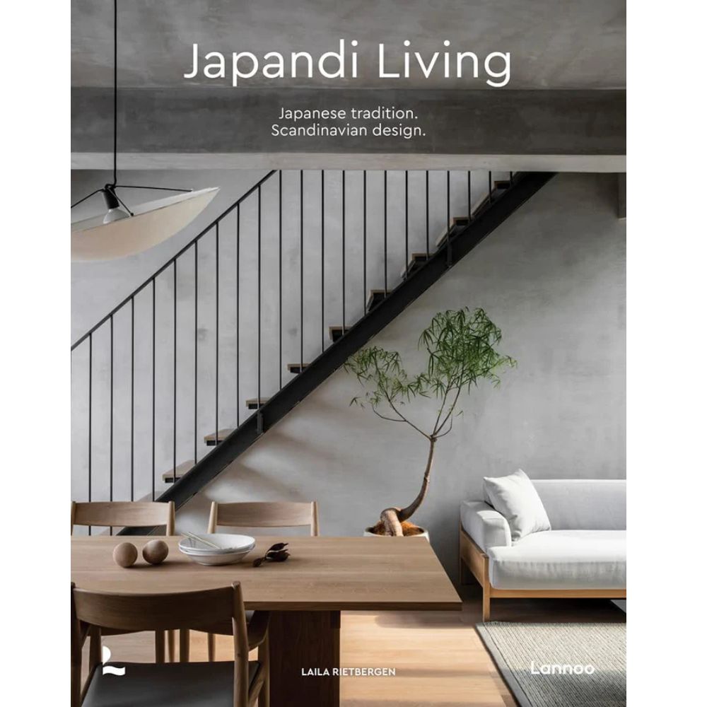על עטיפת הספר "Japandi Living" של Fine Lab Home מופיעים רהיטים מודרניים מעץ, עציץ וגרם מדרגות, עם הכיתוב: מסורת יפנית. עיצוב סקנדינבי.