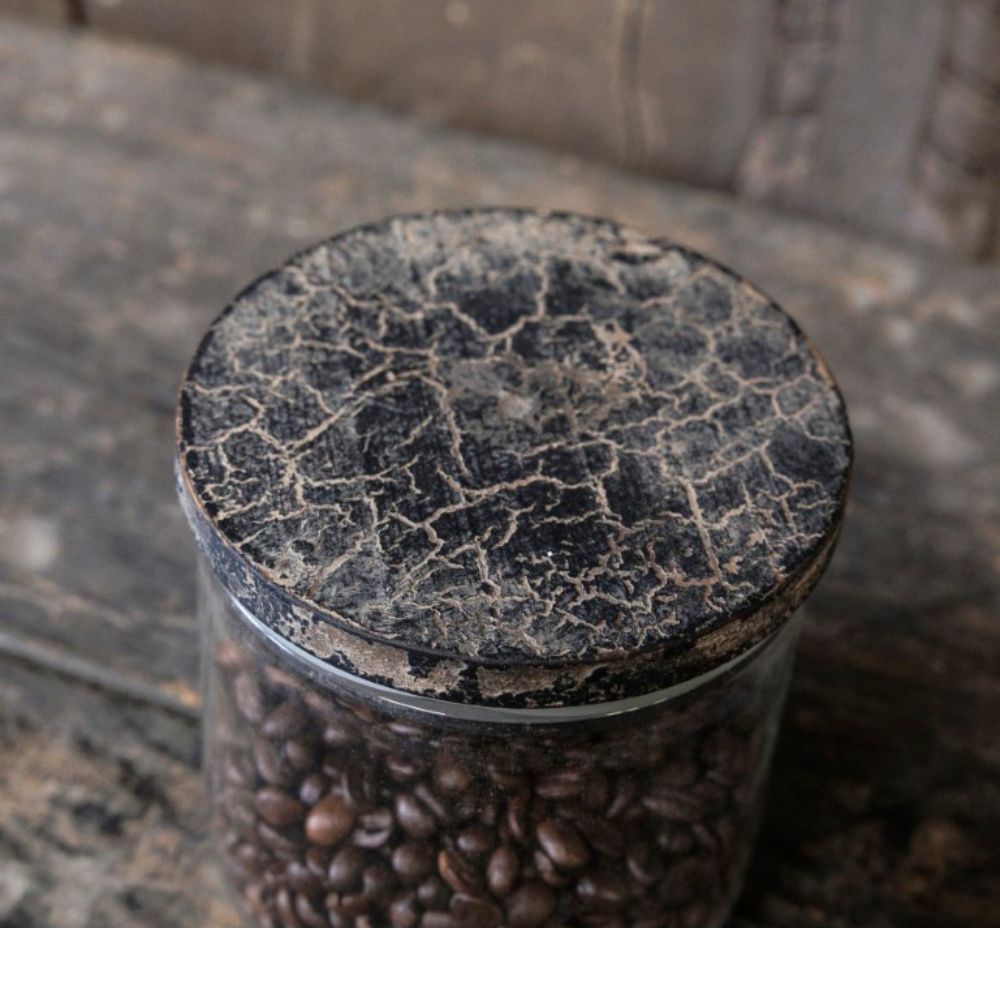 צנצנת זכוכית עם מכסה עץ - בשלושה גדלים מבית Fine Lab Home, מלאה בפולי קפה, מונחת על משטח עץ ומכוסה במכסה עגול בעל מראה טבעי ומיושן.