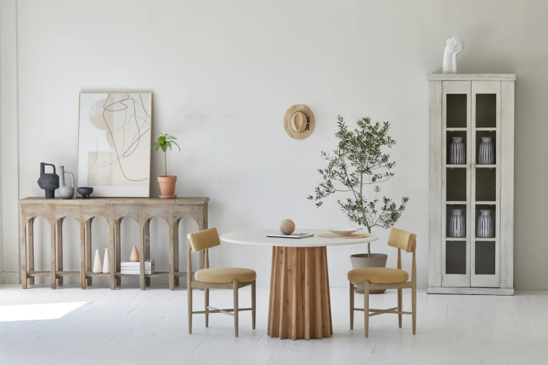 קונסולה נורדית עץ מבית Fine Lab Home ניצבת על רקע קיר לבן, מעוצבת עם שתי קערות, ספרים ערוכים ועיצוב דקורטיבי; לצדהן כיסא בר, תיק תלוי ועלה מיובש המוסיפים נגיעה מודרנית.