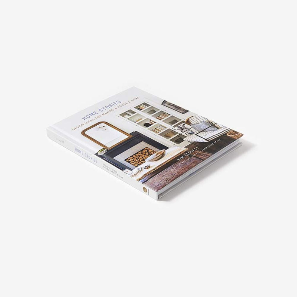 הספר "Home Stories" בהוצאת Fine Lab Home, בכריכה קשה, שעל כריכתו מופיעים תמונות מעוצבות של עיצוב פנים, מונח על משטח לבן — אידיאלי להשראה לבית.