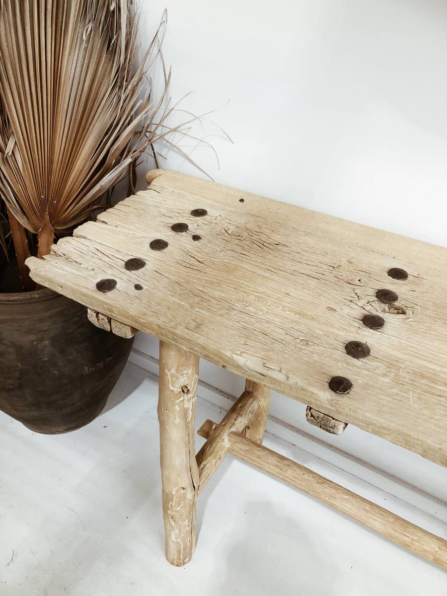 הקונסולה עץ ניטים מבית Fine Lab Home היא ספסל עץ כפרי בעל גימור טבעי גס, טקסטורת עץ בולטת, ארבע רגליים לא אחידות ומתיחה אופקית, המיוצר כריהוט ידידותי לסביבה.