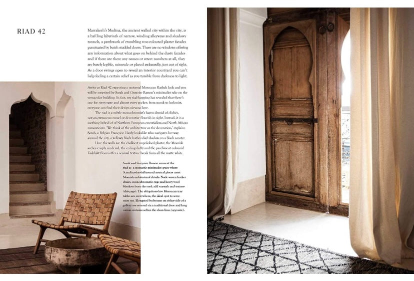 פינה נעימה עם כריות מעוצבות, קירות לבנים ומנורת תלייה ארוגה, בה מוצג ספר העיצוב nomad at home של Fine Lab Home — מושלם לחובבי עיצוב הבית.