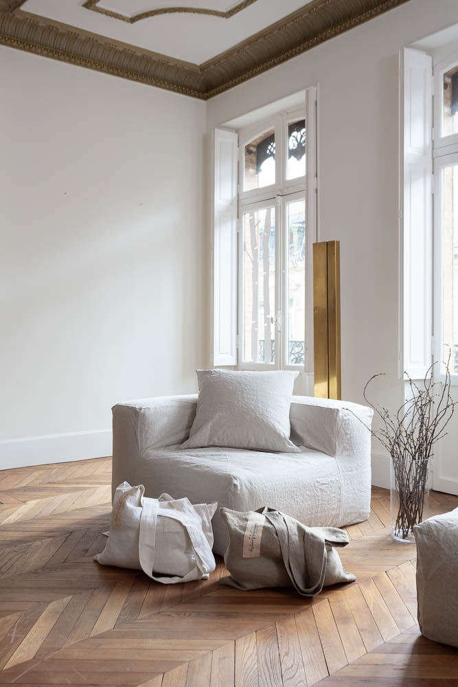 תיק פשתן של Fine Lab Home הוא תיק נשיאה מלבני בצבע לבן-שמנת, עם שתי ידיות רחבות ותווית קטנה בצבע בז' עם כיתוב בכתב יד.