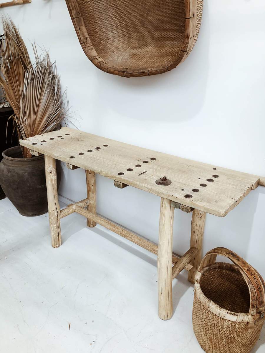 הקונסולה עץ ניטים מבית Fine Lab Home היא ספסל עץ כפרי בעל גימור טבעי גס, טקסטורת עץ בולטת, ארבע רגליים לא אחידות ומתיחה אופקית, המיוצר כריהוט ידידותי לסביבה.