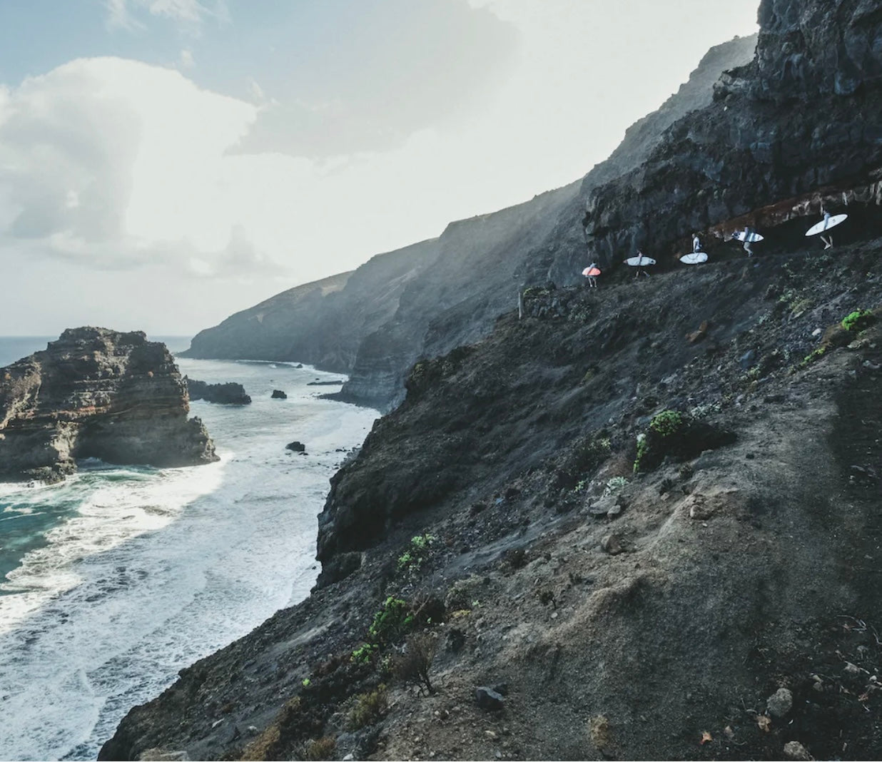 ספר העיצוב "The Surf Atlas" בכריכה קשה מבית Fine Lab Home כולל תמונת שער של גולש גלים בתוך גל כחול ענק.