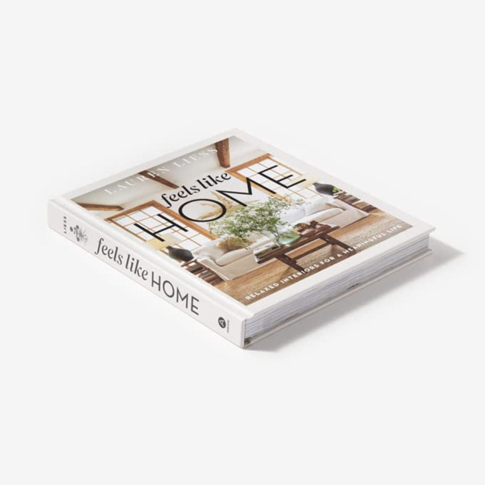 ספר עיצוב בכריכה קשה מבית Fine Lab Home, "feels like home" (מרגיש כמו בבית), מציג על הכריכה סלון עם עיצוב ניטרלי ותאורה טבעית.