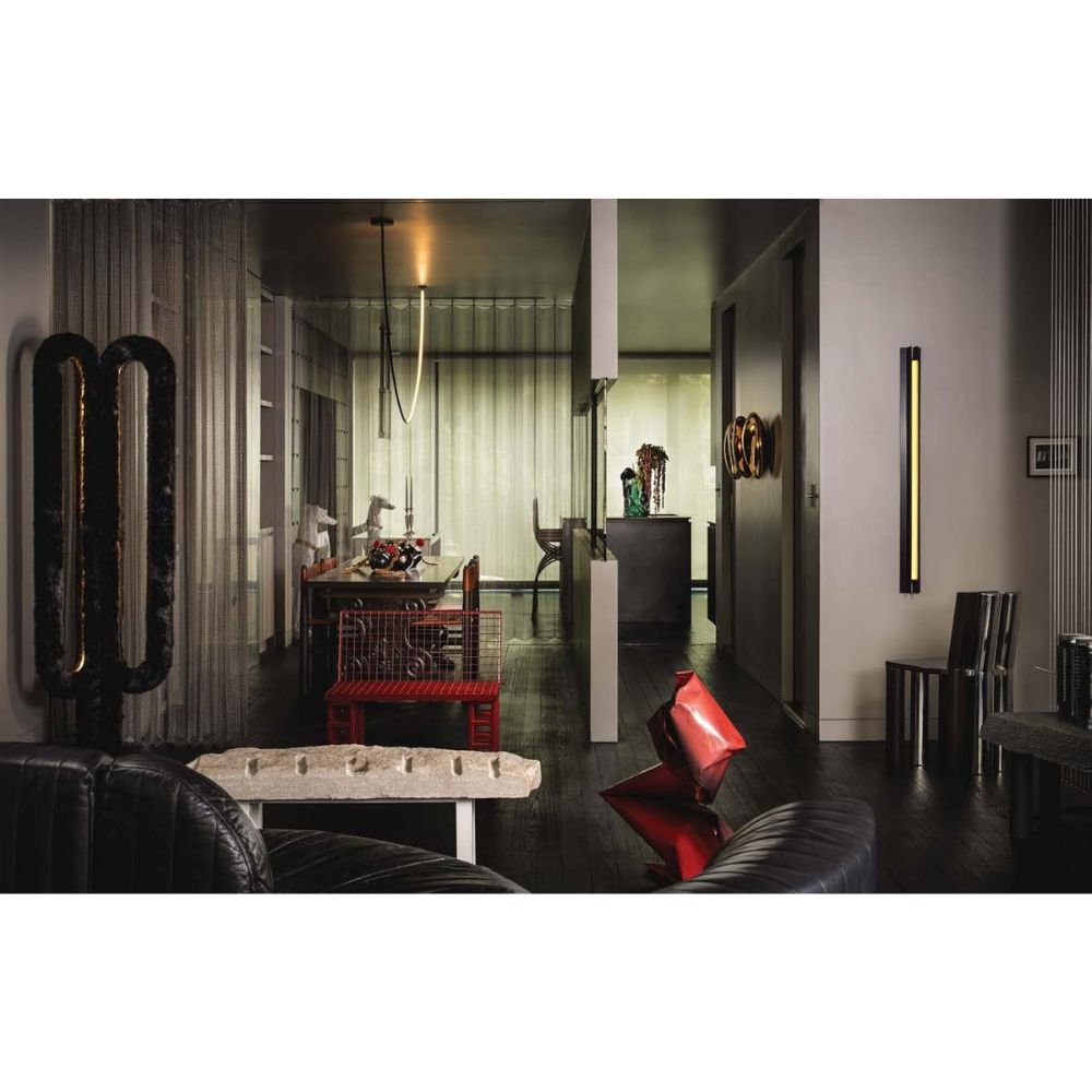 סלון מודרני המעוצב בריהוט אקלקטי, בהשראת ספר העיצוב New York Interiors של Fine Lab Home, הכולל ספסל אבן, כיסאות עור שחורים, שולחן צד אדום ווילונות שקופים המחלקים את החלל באלגנטיות.