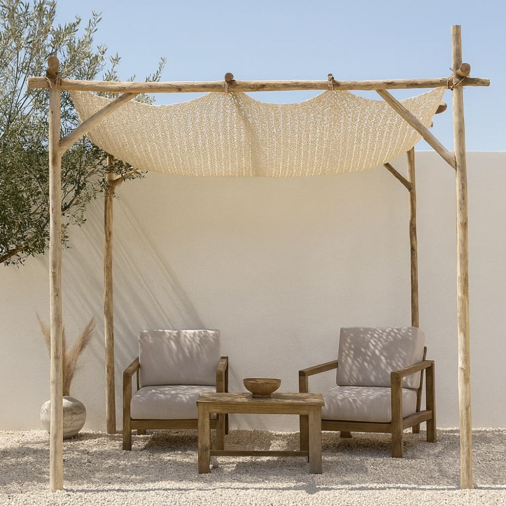 סככת עץ פשוטה עם גג רשת של Fine Lab Home רשת הצללה- רשת צל לחצר ולגינה עומדת על מדשאה ירוקה, מוקפת עצים ושמיים כחולים וצלולים.