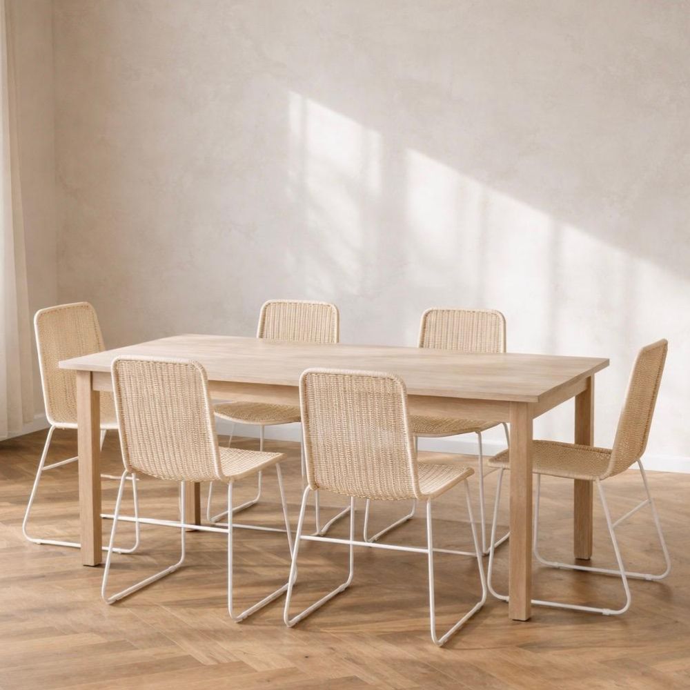 שולחן אוכל מלבני מעץ עם שישה כיסאות אוכל מראטן עם רגלי מתכת של Fine Lab Home, על רצפת עץ בחדר מינימליסטי ומואר באור השמש.