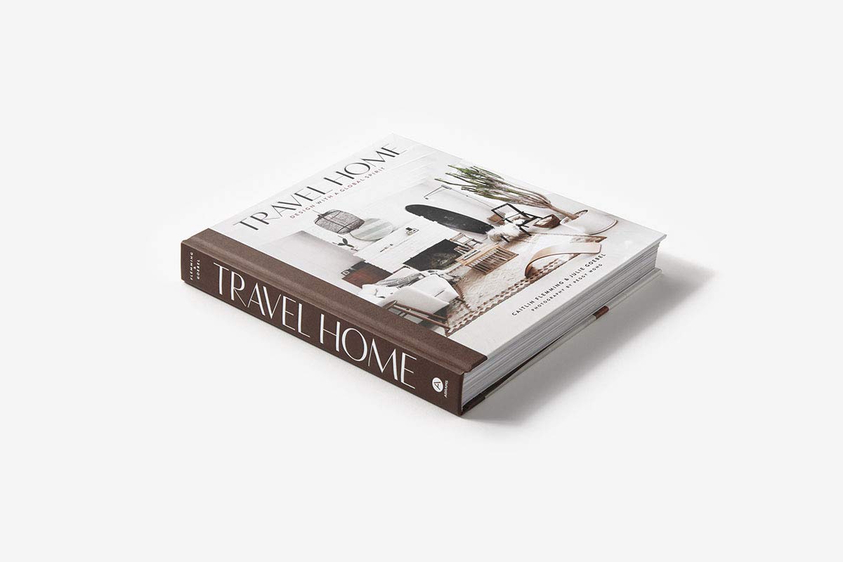 הספר בכריכה קשה ספר עיצוב travel home מאת Fine Lab Home מוצג על משטח לבן, וכריכתו מציגה עיצוב פנים מסוגנן ומודרני של סלון – ספר השראה מושלם לאוהבי עיצוב הבית.