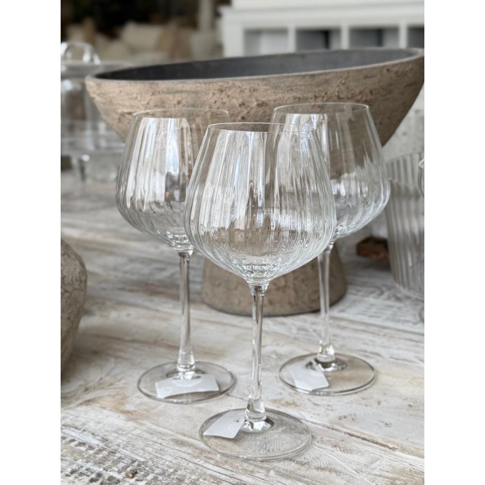 שלוש כוסות יין מסדרת "כוס גביע ליין" - 665 מ"ל (סט של 4 יחידות) מבית Fine Lab Home מונחות על שולחן עץ כפרי עם קערת אבן גדולה וקישוט ברקע.