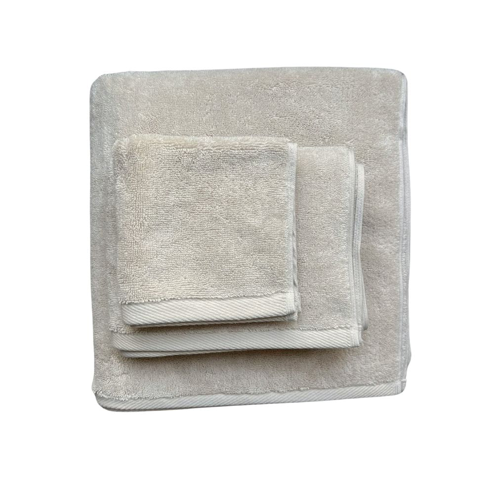 ערימה מקופלת בקפידה של שלוש מגבות גוף איכותיות של Fine Lab Home - צבע חול בגדלים שונים, מושלמות לכל חלל, מוצגות על רקע לבן.