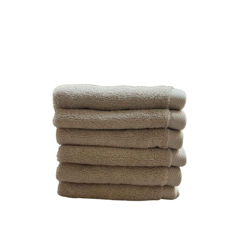 ערימה של שש מגבות ידיים בצבע בז' מקופלות בקפידה (מארז 6 מגבות ידיים - צבע חול) מבית Fine Lab Home, עשויות מכותנה סרוקה, על רקע לבן חלק.