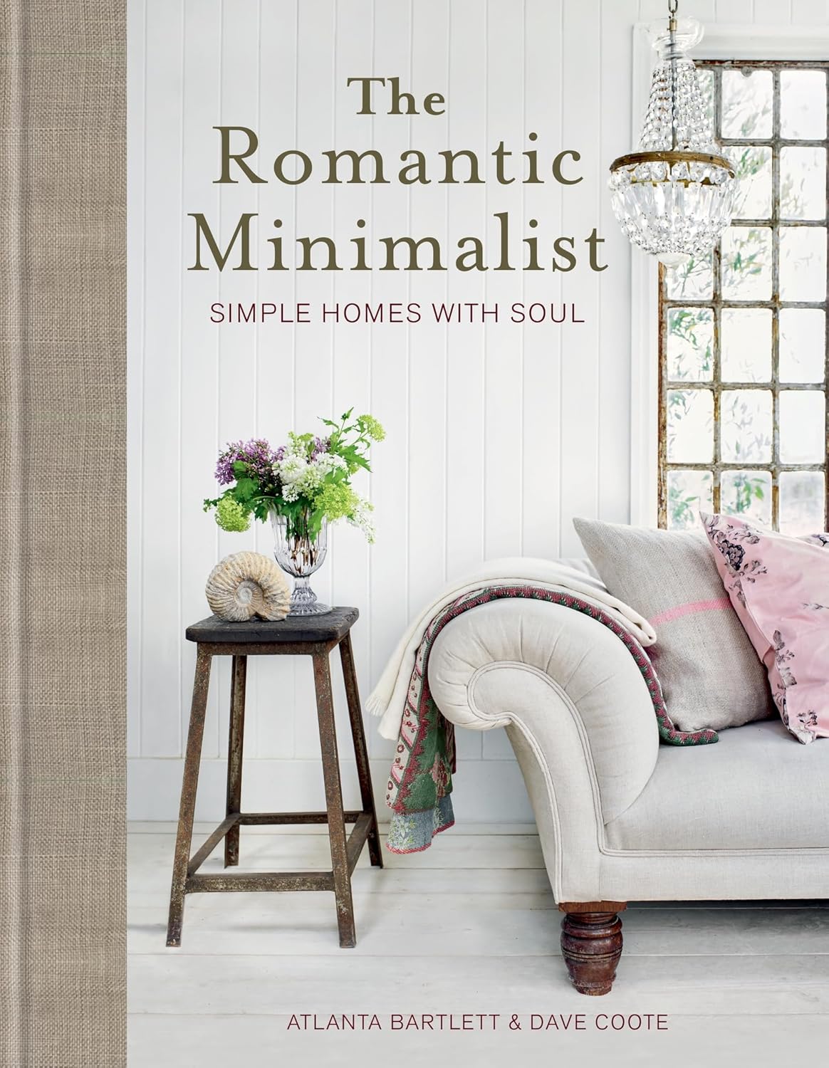 הספר עיצוב The Romantic Minimalist: Simple Homes with Soul מאת Fine Lab Home כולל עטיפה נעימה עם שרפרף, סידור פרחים, צדף, ספה ונברשת. מחברים: אטלנטה ברטלט ודייב קוט.