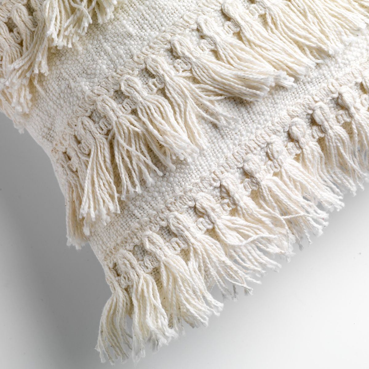 תקריב של כרית הנוי המלבנית הלבנה מדגם "Fara" מבית Fine Lab Home, המציגה שורות של ציצית קשורה ודוגמאות אריגה המעניקות מרקם וסגנון לכל חלל.