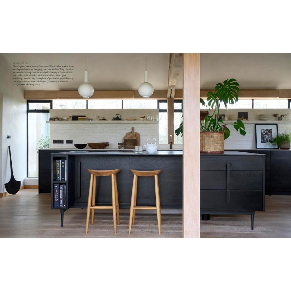 מטבח מודרני עם ארונות כהים, אי מרכזי, שרפרפים מעץ, מנורות תלייה, צמחים וחלונות גדולים ליצירת מראה טבעי. בהשתתפות: ספר העיצוב "Bring the Outside In" מאת Fine Lab Home, ליצירת חיבור לטבע.