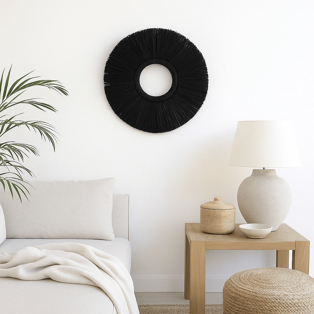 סלון בגוונים ניטרליים עם ספה לבנה, שולחן צד מעץ, מנורה בצבע בז', סלסלה קלועה טבעית, ומעליה קישוט קיר עגול - קש שחור של Fine Lab Home.